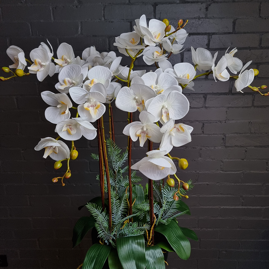 Белые, искусственные фаленопсисы в графитовом кашпо.