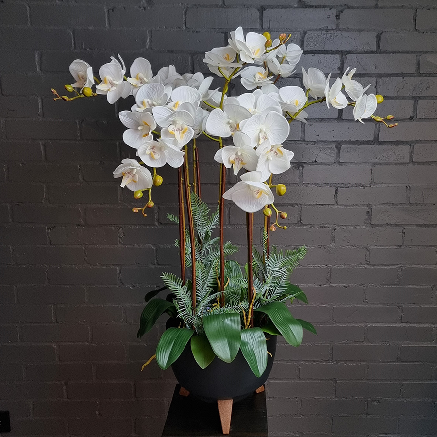 Белые, искусственные фаленопсисы в графитовом кашпо.
