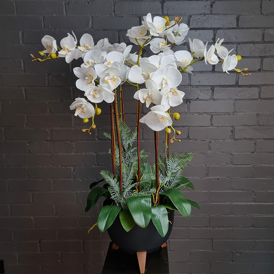 Белые, искусственные фаленопсисы в графитовом кашпо.