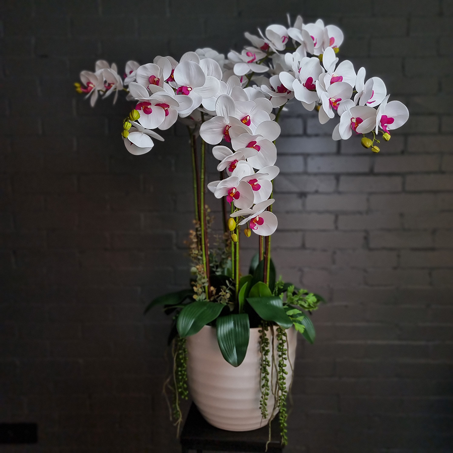 Композиция из 7 искусственных фаленопсисов в белом керамическом кашпо.